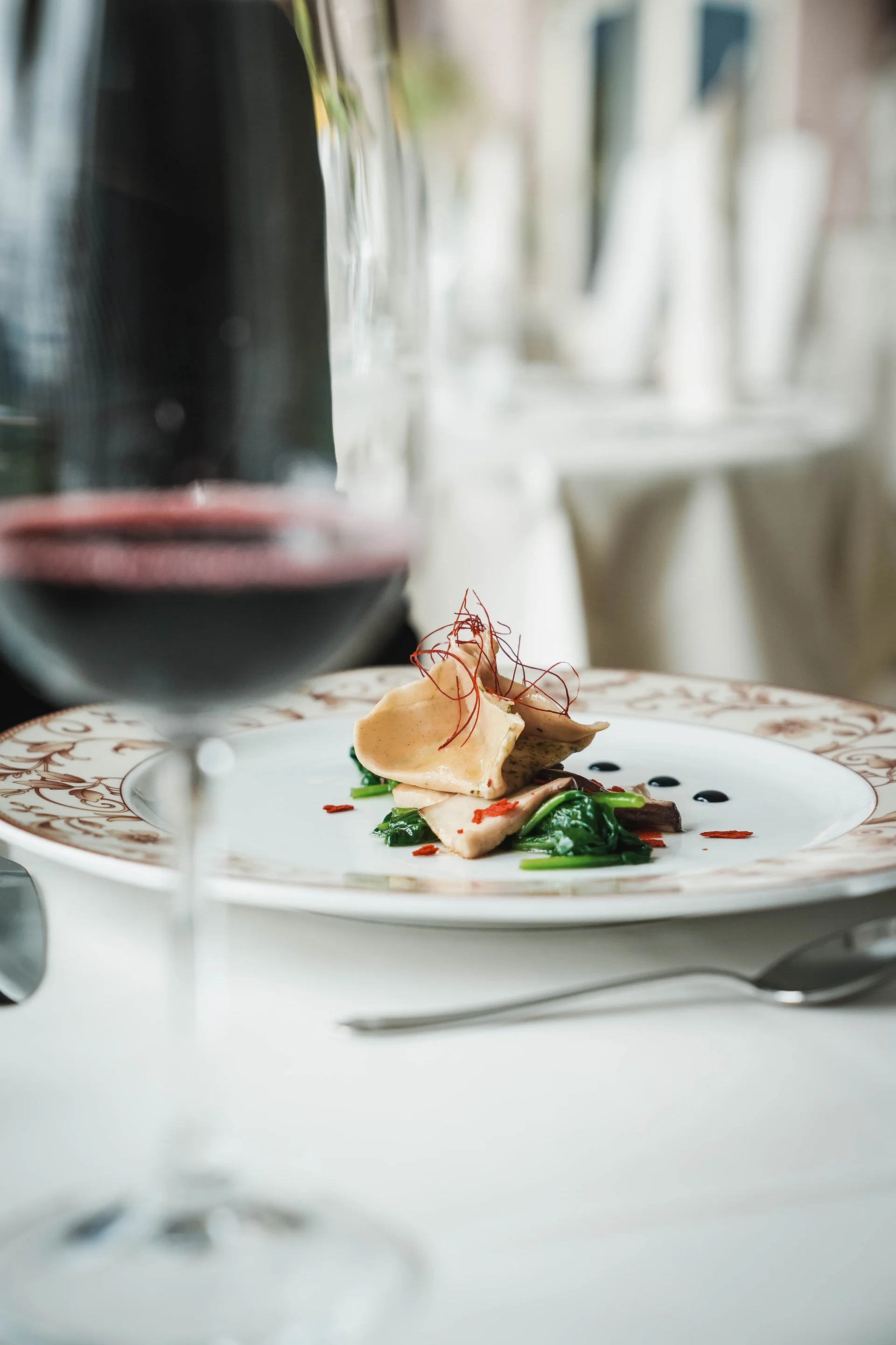 Gourmetgericht mit Pasta und Spinat auf einem dekorativen Teller