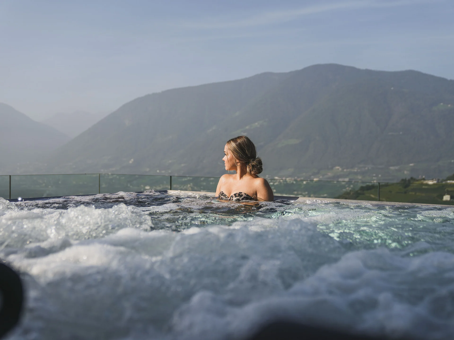 Frau entspannt im sprudelnden Whirlpool mit Bergblick