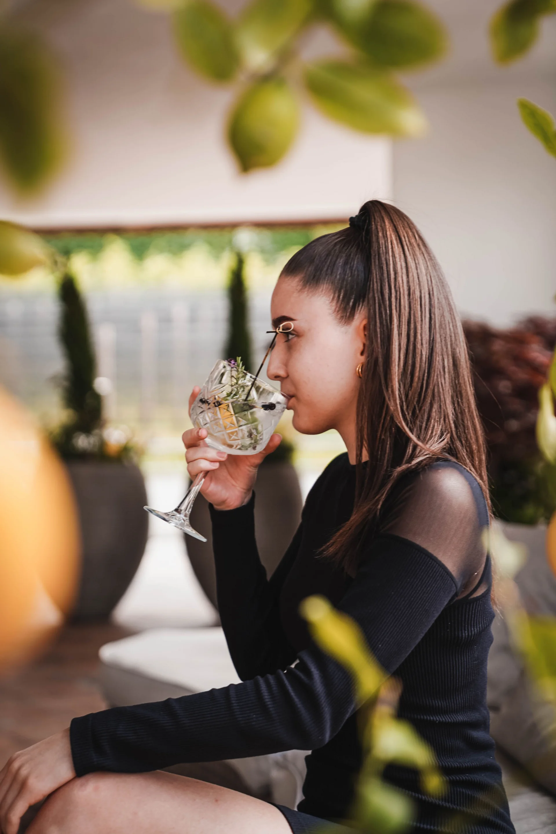 Das Herzstück des Kröll: unsere Bar und Lounge Frau trinkt aus einem Weinglas mit Kräutern und Zitrone