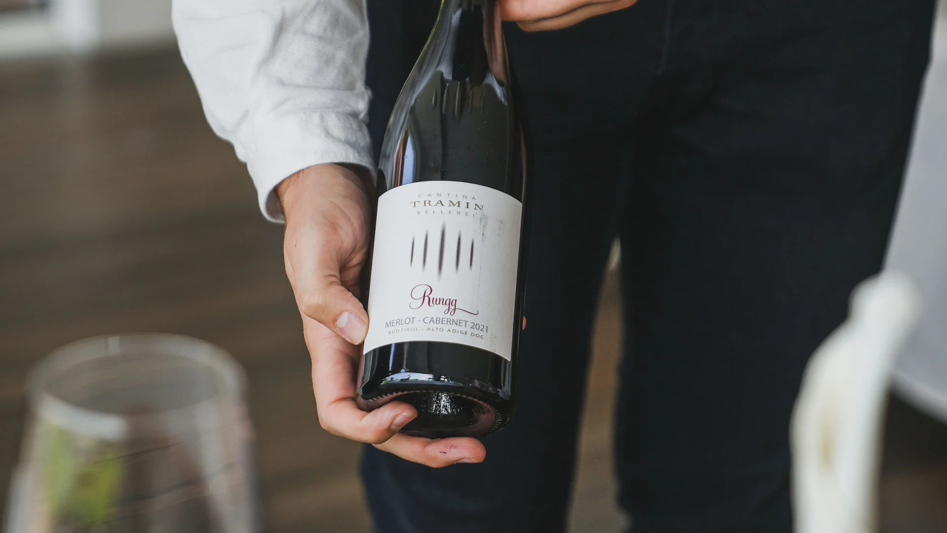 Impressionen in #echtzeit Person hält eine Flasche Rotwein über einem gedeckten Tisch