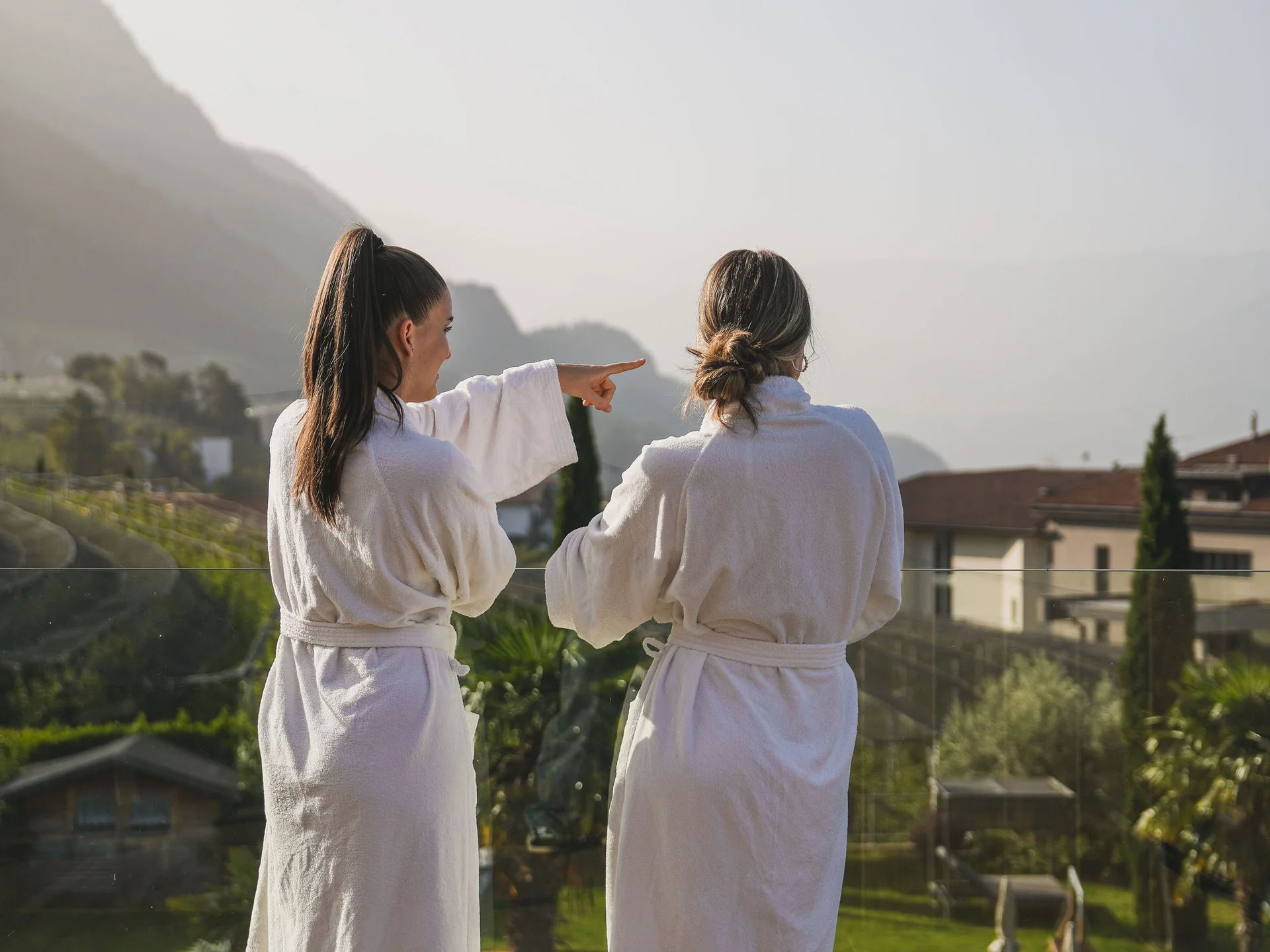 Euer Hotel in Schenna für Momente in #echtzeit Zwei Frauen in Bademänteln genießen den Ausblick auf Pool und Berge