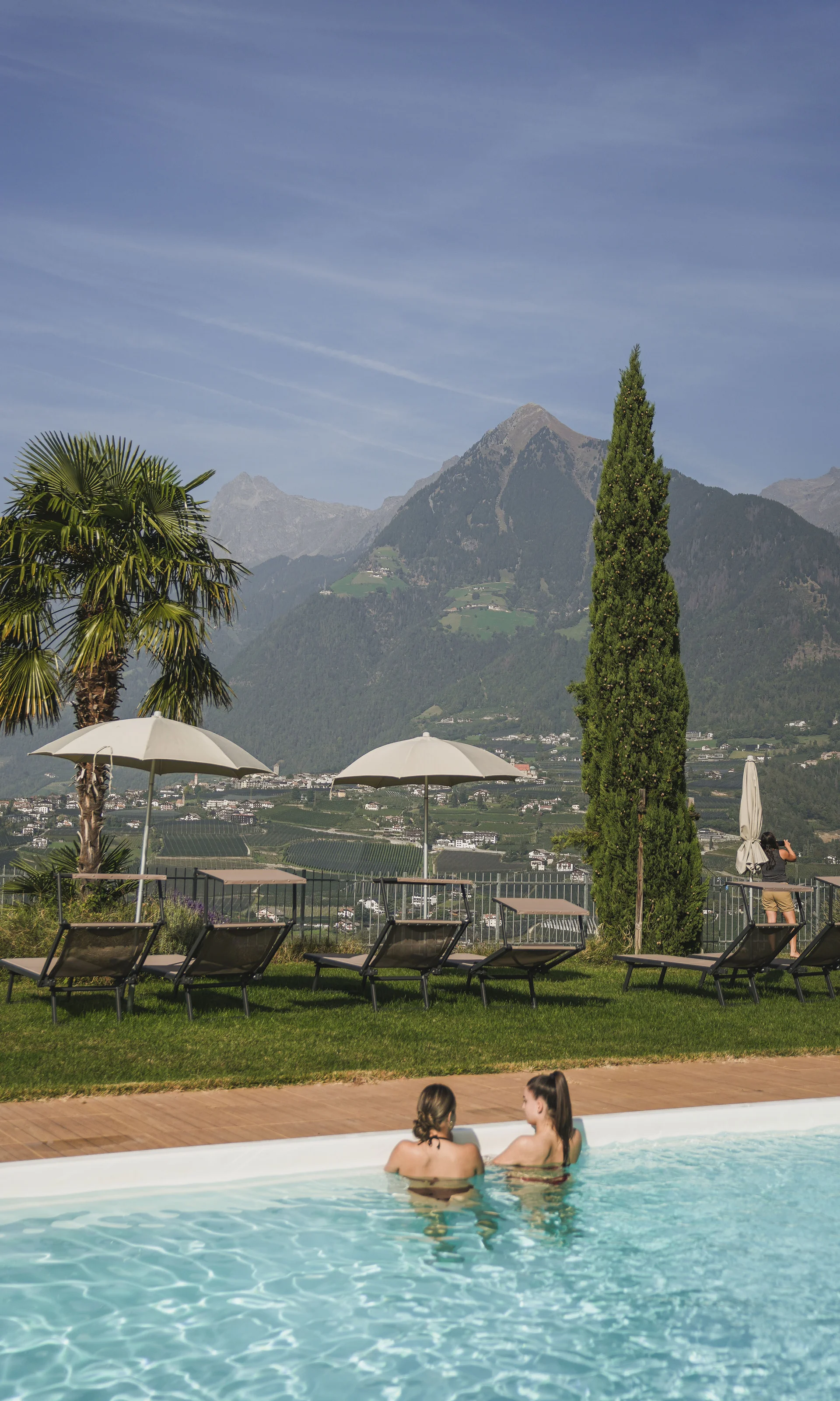 Zwei Frauen genießen Pool mit Bergblick und Liegestühlen im Garten