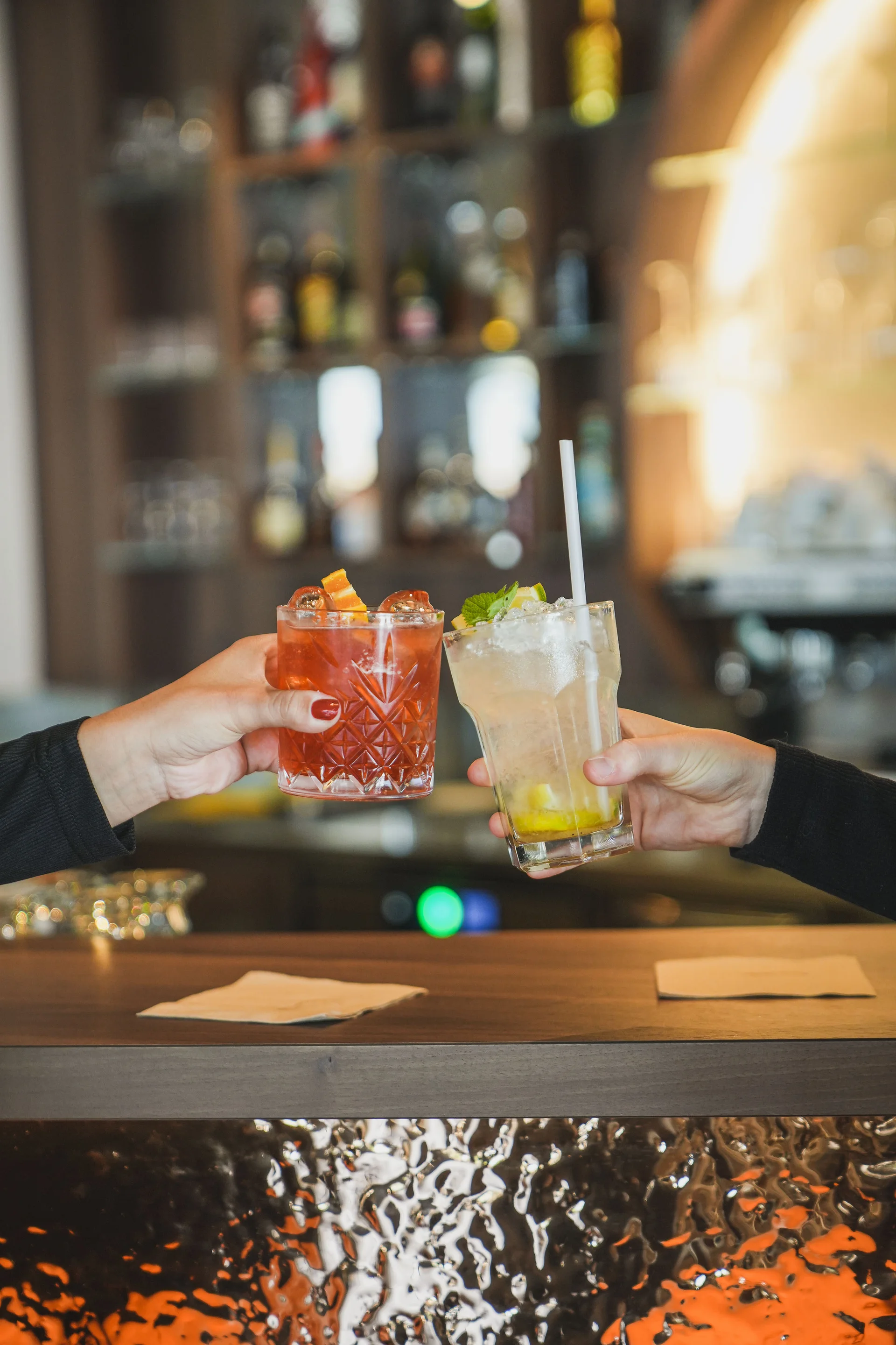 Echt genießen im Hotel mit ¾-Pension Zwei Hände stoßen mit Cocktails in einer Bar an