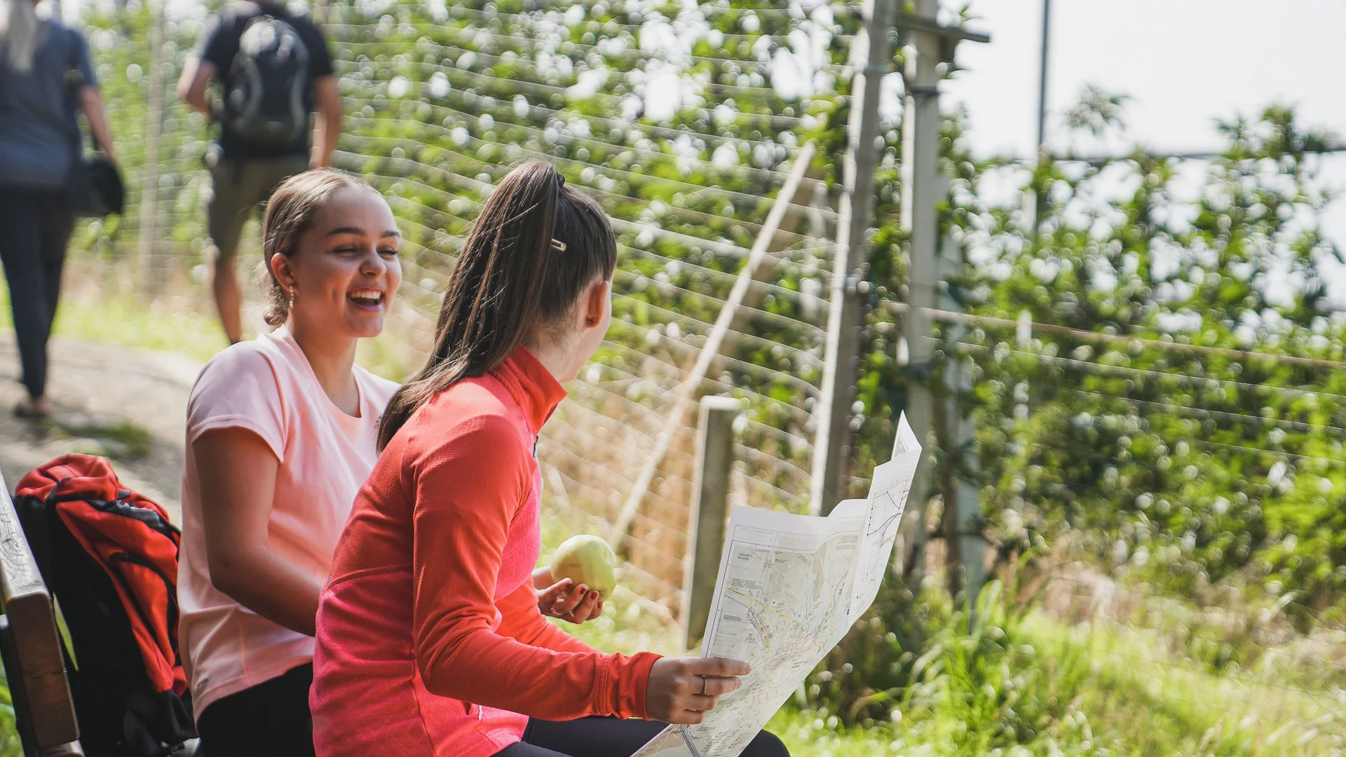Impressionen in #echtzeit Zwei Frauen sitzen auf einer Bank, eine hält eine Karte, beide lachen