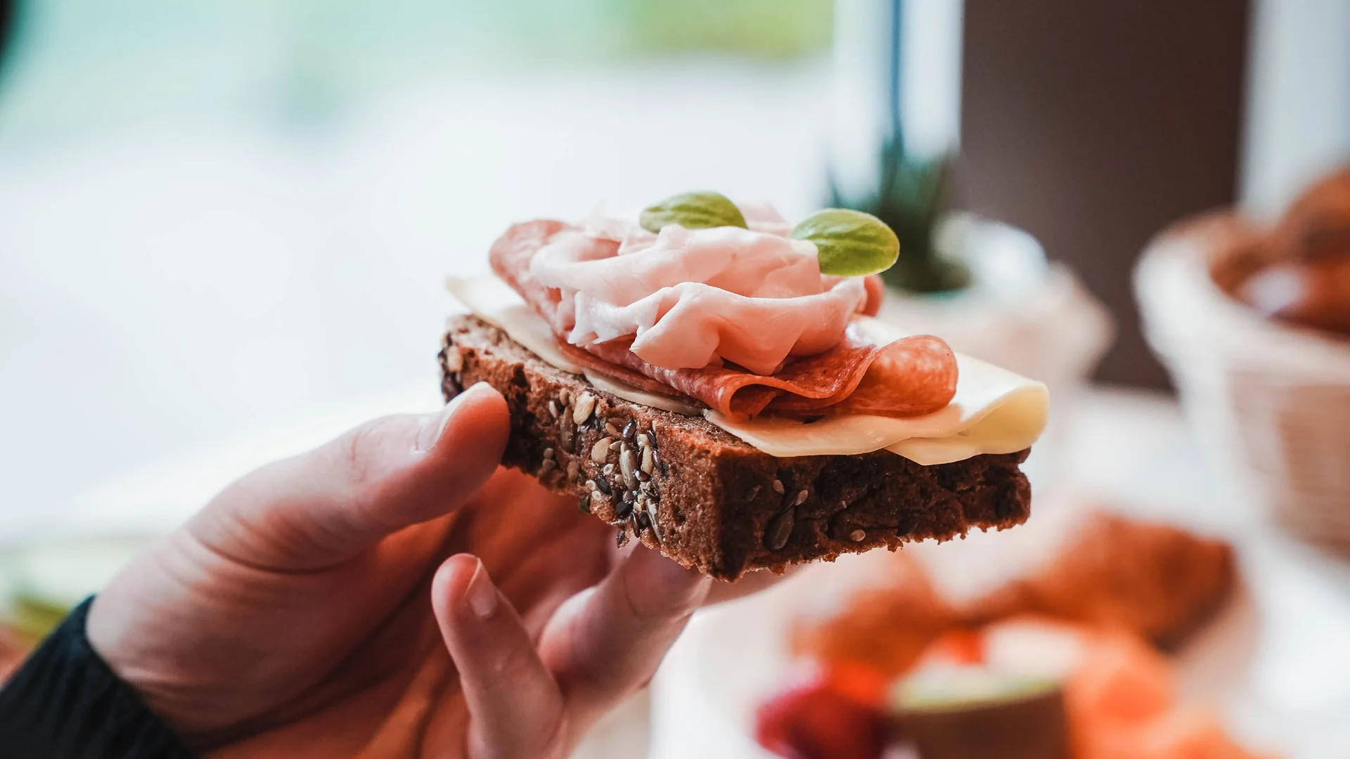 Impressionen in #echtzeit Hand hält ein belegtes Vollkornbrot mit Wurst und Käse