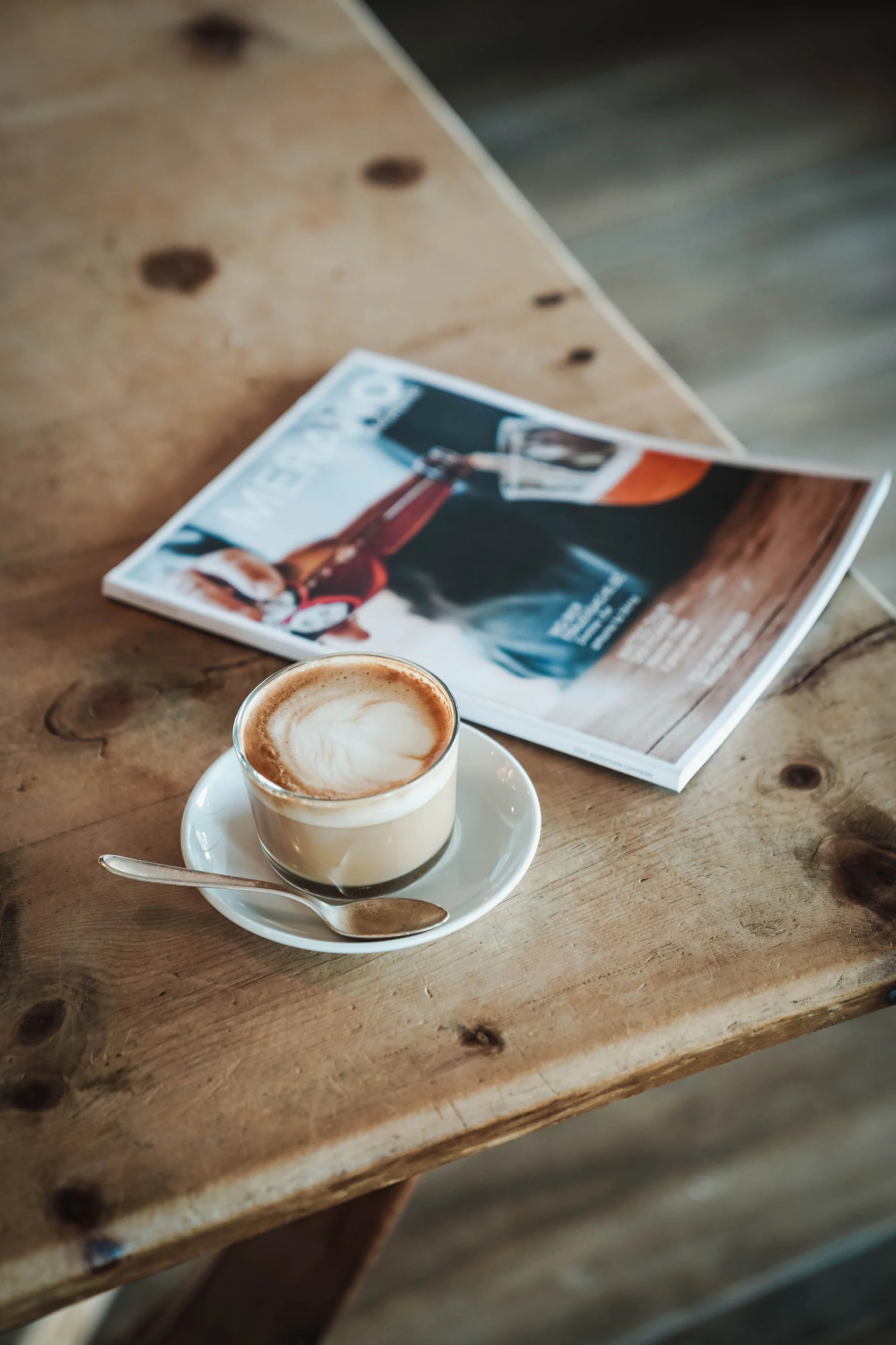 Das Herzstück des Kröll: unsere Bar und Lounge Tasse Kaffee mit Löffel auf Holztisch neben Magazin