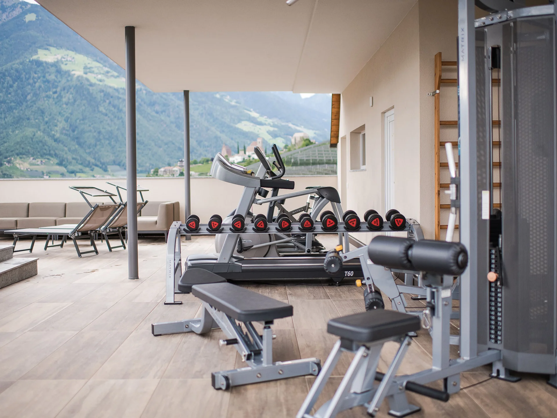 Fitnessgeräte auf überdachtem Balkon mit Bergblick