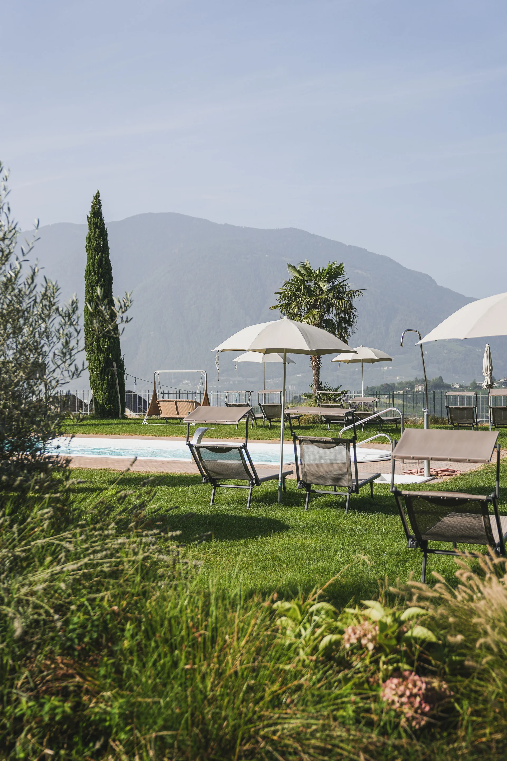 Poolbereich mit Liegestühlen und Sonnenschirmen vor Bergen